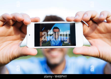 Photo of a young smiling man taking a selfie with his mobile Stock Photo