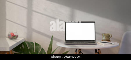 Open laptop with blank screen on white table in loft workspace Stock Photo
