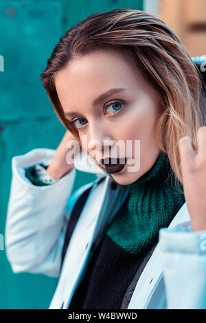 Blue-eyed fashion model with dark lipstick posing outside Stock Photo