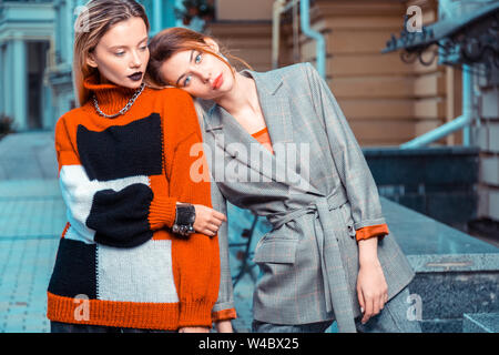 Model wearing grey suit leaning on shoulder of colleague