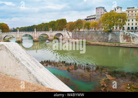 Image of Rione Ponte district. View of white Ponte Sant'Angelo bridge and its reflection, orange trees, green waters of Tiber river under dramatic clo Stock Photo