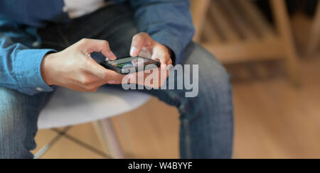 Young male UI developer holding smartphone in relaxing working space Stock Photo