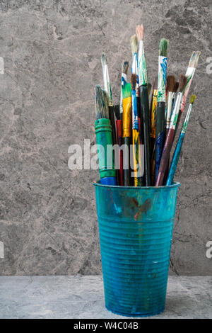 Dirty plastic flask with assorted painting brushes Stock Photo
