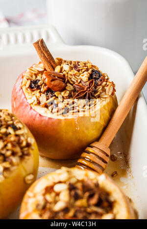 Baked apples with granola, cranberries, nuts and honey in the oven dish. Stock Photo