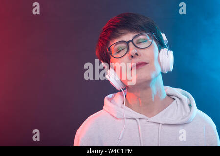 Hobby and leisure concept - Middle-aged woman listening music on blue background. Stock Photo