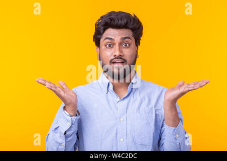 Portrait of a young Indian surprised man with dew in a shirt dosing against a yellow background. Concept of news and advertising. Stock Photo