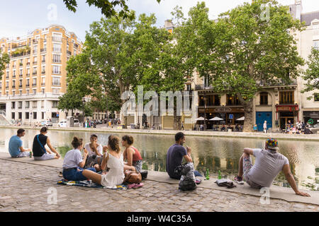 Paris Canal Saint Martin - People sitting along the Canal Saint Martin in the 10th arrondissement of Paris, France, Europe. Stock Photo