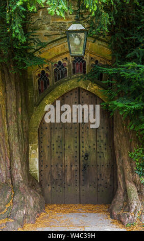 The north wooden door of St Edward's Church in Stow on the Wold in Gloucestershire with ancient yew trees either side Stock Photo