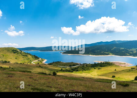 Beautiful panorama landscape with golden sun and meadow at sunset. Sun rays shine behind mountains. Stock Photo