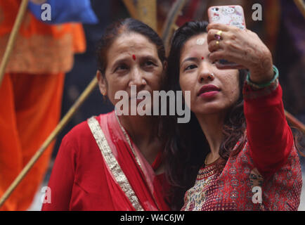 Kathmandu, Nepal. 22nd July, 2019. Women take selfies after giving offering to the Hindu god Lord Shiva, the god of destruction and creation at the Shiva temple during a Shrawan Sombar festival.Shrawan month is considered as the holiest month of the year and each Somvar (Monday) of this month is known as Shrawan Somvar, during which devotees fast and worship Lord Shiva to pray for happiness for their families. Credit: SOPA Images Limited/Alamy Live News Stock Photo