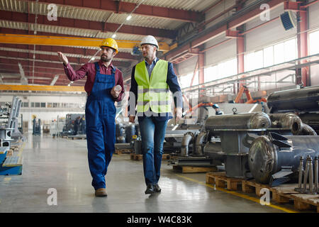 Engineers walking along the plant they work at shot from distance. Stock Photo