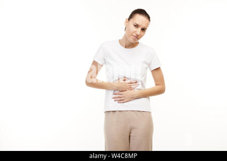 Woman in white t-shirt having strong stomach aches. Stock Photo