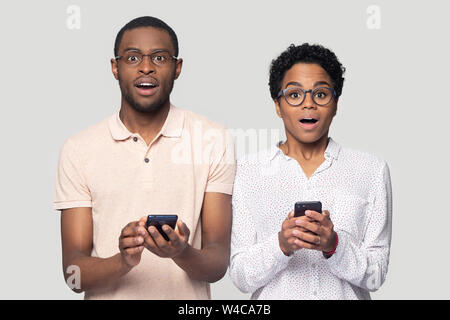 Amazed ethnic couple surprised by message on smartphone Stock Photo