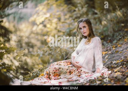 Portrait of beautiful pregnant woman in autumn forest. Stock Photo