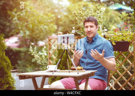Man vlogger using smart phone while recording video for feed vlog Stock Photo