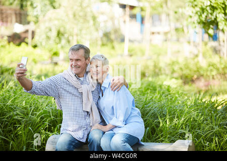 Portrait of loving senior couple posing for selfie photo while enjoying date in park, copy space Stock Photo