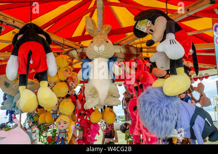 Large cuddly toy prizes hanging from wooden tent beams at a stall at a funfair. Stock Photo