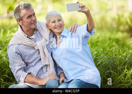 Portrait of loving senior couple taking selfie photo while enjoying date in park, copy space Stock Photo