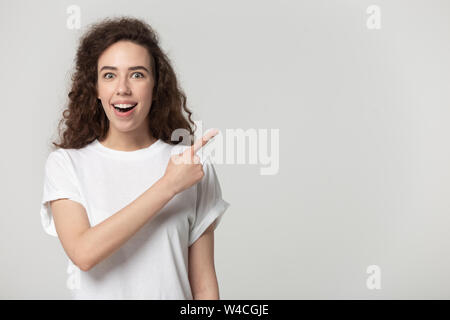Surprised woman pointing finger at copy space studio shot Stock Photo