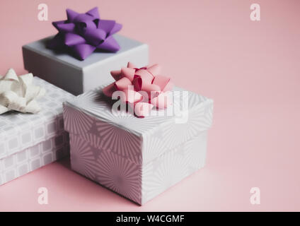 Three light gray gift boxes with colorful bows on pink background. Festive concept. Stock Photo