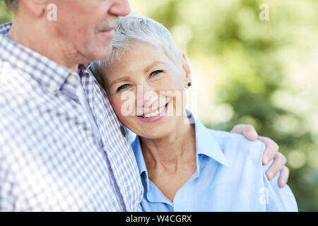 Mid-section portrait of loving senior couple embracing, focus on elegant woman smiling at camera, copy space Stock Photo
