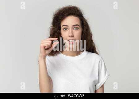 Woman look at camera showing with fingers something small Stock Photo