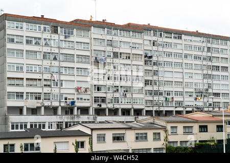 Serial apartments building facade with windows and hanging clothes. Old building construction in Spain Stock Photo