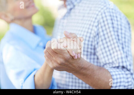 Close up of loving senior couple holding hands while dancing together outdoors, copy space Stock Photo
