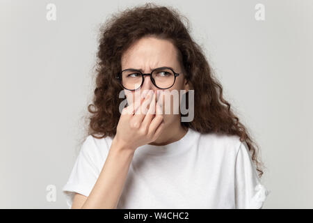 Headshot portrait girl plugs nose feels unpleasant smell studio shot Stock Photo