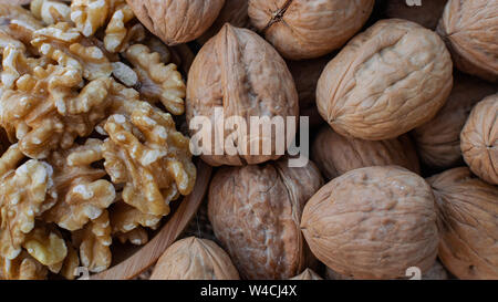 Walnuts in wooden round bowl, and walnuts with shell on sack surface Stock Photo