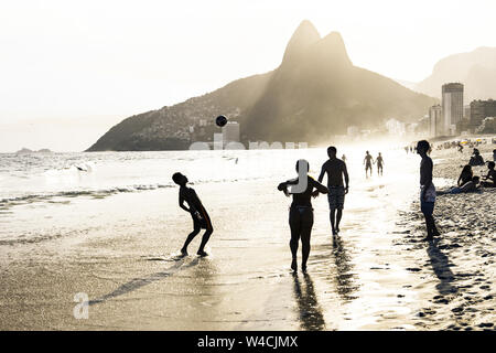 RIO DE JANEIRO, BRAZIL - FEBRUARY 24, 2015: A group of Brazilians playing on the shore of Ipanema Beach, with the famous Dois Irmaos mountain behind them Stock Photo
