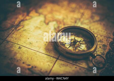 Vintage Adventure Concept. Antique Compass on the Aged World Map. Closeup Photo. Expedition Journey. Stock Photo