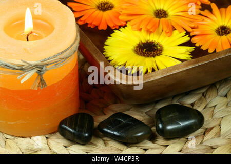 Spa in orange color: candle, calenula flowers and pebbles Stock Photo