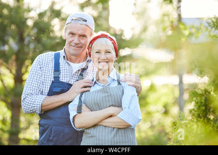 Waist up portrait of senior couple smiling at camera and posing while working at farm, copy space Stock Photo