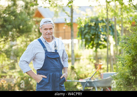 Waist up portrait of senior man smiling at camera and posing while working at farm, copy space Stock Photo
