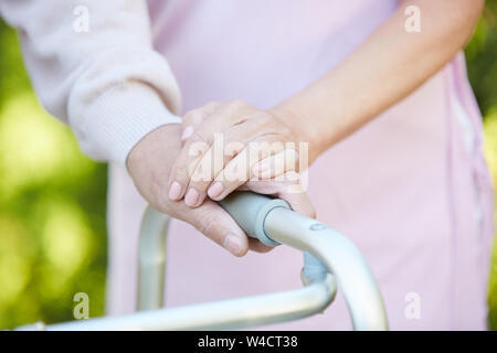 Closeup of caring wife holding hand of husband using walker, copy space Stock Photo