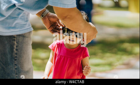 Asian toddler wearing sunglasses  given by the adult in the park. Stock Photo