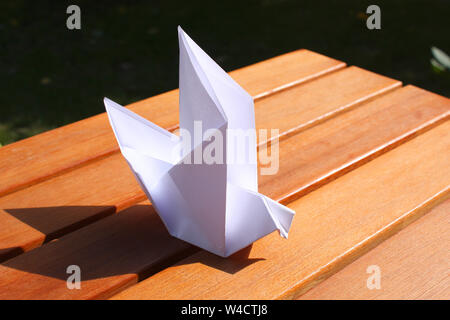 Origami paper bird on wooden table Stock Photo