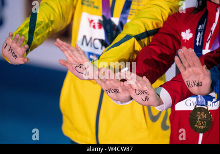 Gwangju, South Korea. 22nd July, 2019. Swimming World Championship: 100 Meter Butterfly Final: Second placed Sarah Sjöström from Sweden, winner Margaret Macneil from Canada and third placed Emma McKeon from Canada have written the words 'I kee never give up Rikako' on their hands for the award ceremony. Credit: Bernd Thissen/dpa/Alamy Live News Stock Photo