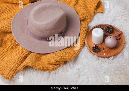 Creative autumn composition with hat, yellow sweater and candles on the wooden tray Stock Photo
