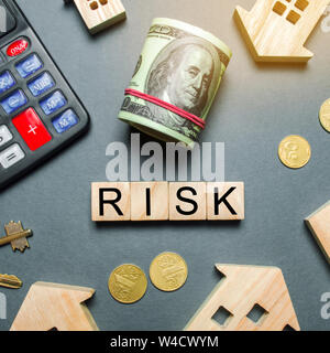 Wooden houses, a calculator, keys, coins and blocks with the word Risk. The risks of investing in real estate. The concept of mortgage risk. Loss of p Stock Photo