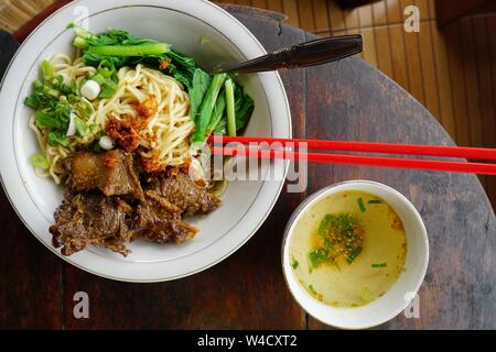 Noodles with Indonesian traditional sauce, chicken or duck sliced, and vegetables. Asian Noodles. Javanese noodles. Stock Photo