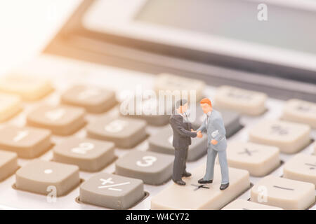 miniature people on calculator and shecking hand,business concept Stock Photo