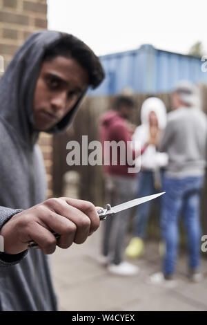 Teenage Boy In Urban Gang Pointing Knife Towards Camera Stock Photo