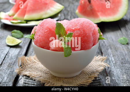 Watermelon ice cream with slices in bowl on wooden table Stock Photo