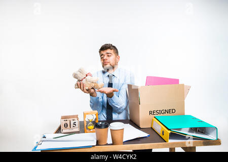 The young man is resigned and folds things in the workplace, folders, documents. Couldn't cope with responsibilities. Concept of office worker's troubles, business, advertising, resignation problems. Stock Photo