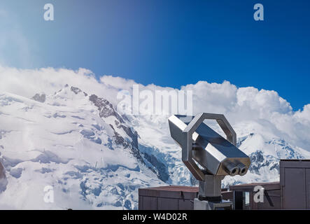 Tourist binoculars close-up over the snowy mountains on sunny day Stock Photo