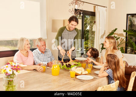 Three generations family having lunch together at the big table at home Stock Photo