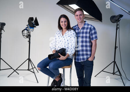 Portrait Of Female And Male Photographers In Studio For Photo Shoot With Camera And Lighting Equipment Stock Photo