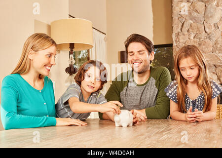 Happy family with two children together saves money with the piggy bank Stock Photo